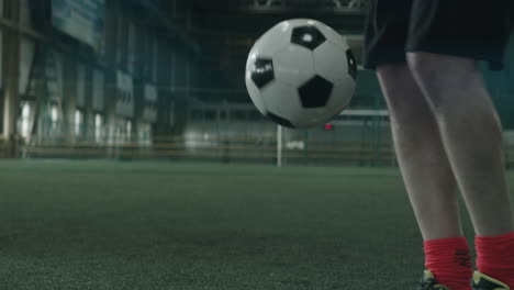 Legs-of-Soccer-Athlete-Juggling-Ball-on-Indoor-Field